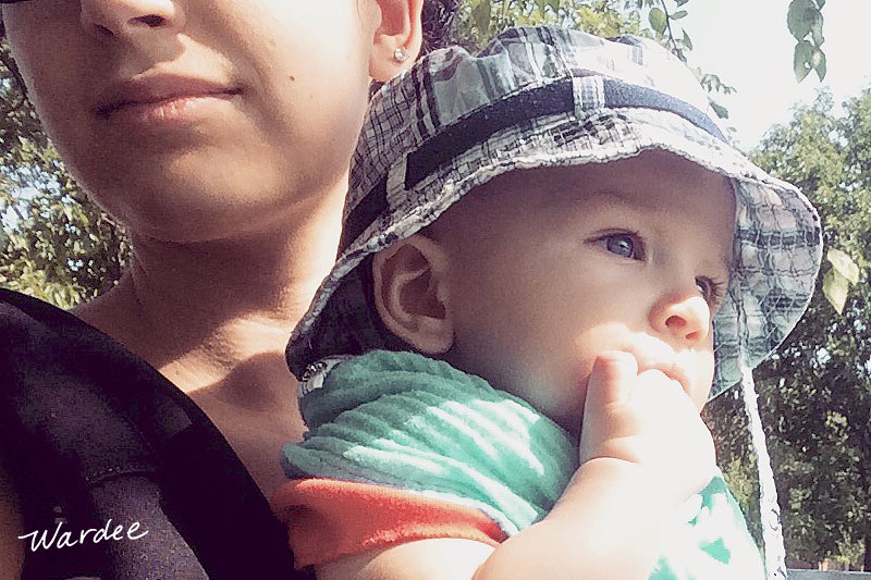 Mother and small child on a summer day. The baby is wearing a sunhat to shade his eyes.