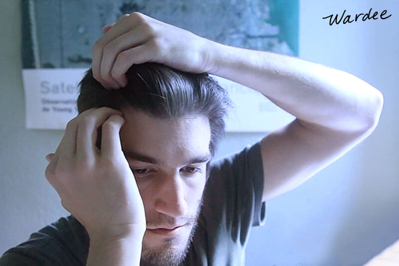 Man massaging his scalp to promote hair growth.