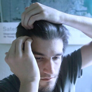 A man massaging his scalp to promote hair growth.