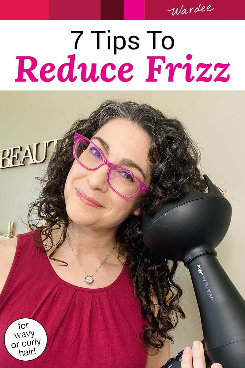 Photo of smiling woman with dark curly hair demonstrating how to use a diffuser. Text overlay says: "7 Tips to Reduce Frizz (for wavy or curly hair!)"