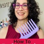 Photo of smiling woman with dark curly hair holding up a purple wide tooth comb. Text overlay says: "7 Ways to Reduce Frizz With 7 Easy Steps (for wavy or curly hair)"