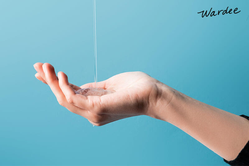 Woman's hand outstretched to catch a drizzle of shampoo.