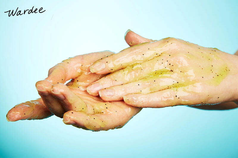 Close-up photo of a woman applying an exfoliating scrub to her hands.