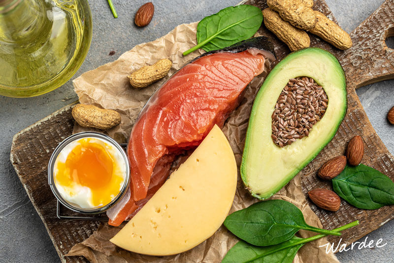 Array of vitamin A rich foods, including eggs, cheese, peanuts, spinach, almonds, flax seeds, and avocado.