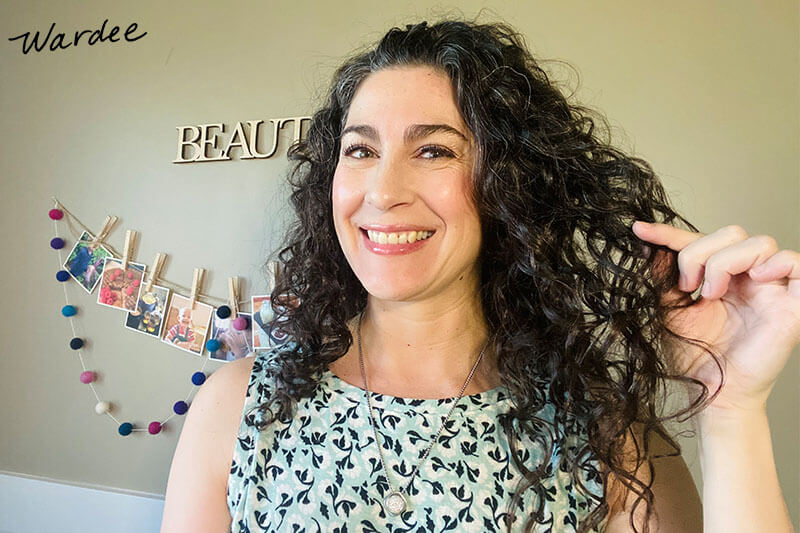 Smiling woman holding up her soft, bouncy curls.