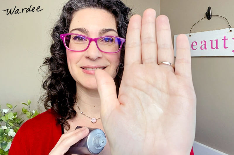 Woman holding up the palm of her hand with a dollop of curl cream on it.