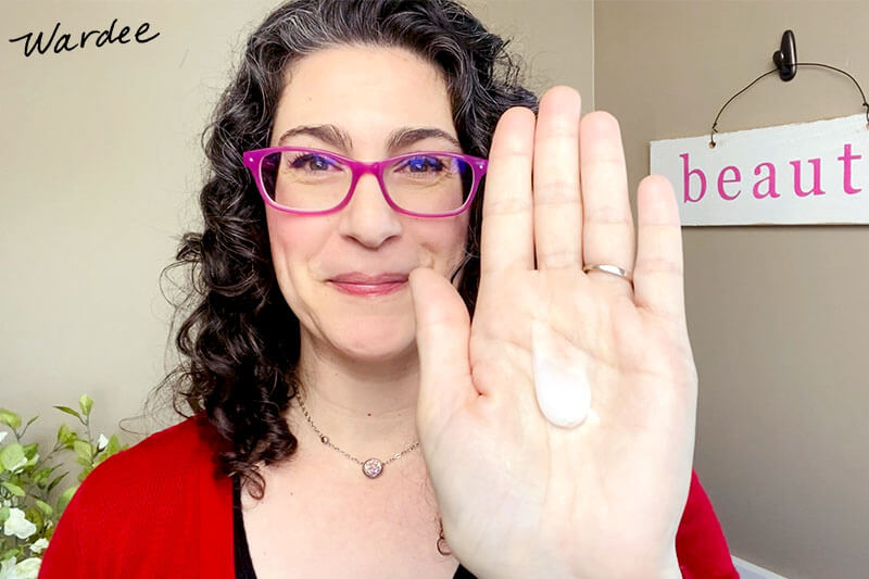 Woman holding up the palm of her hand with a dollop of hair gel on it.