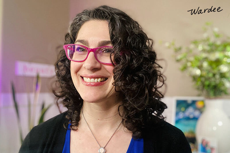 Photo of a smiling woman with curly hair.