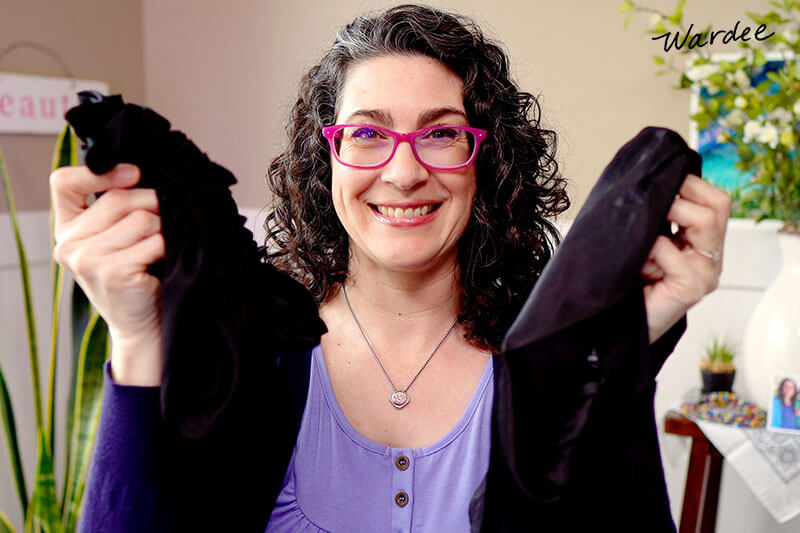 Smiling woman holding up a few examples of silk bonnets.