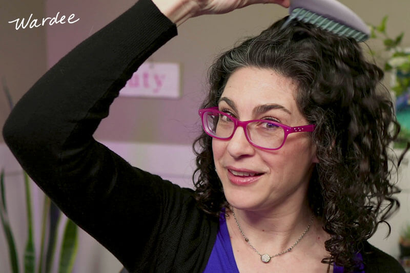 Photo of a woman using a type of comb to add volume to her roots.