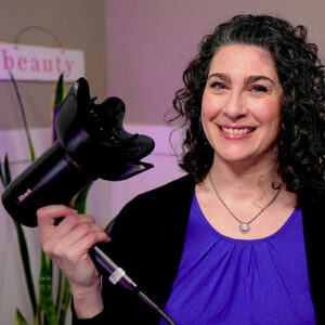 Photo of a smiling woman holding up a black hair diffuser.