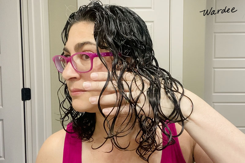 Photo of a woman with wet hair, showing how her curls are in clumps without frizz.